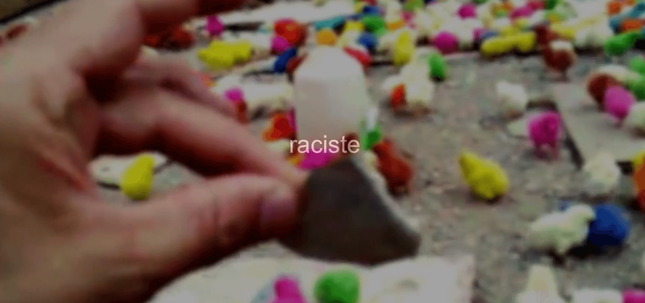 Hand reaching toward colorful objects with 'raciste' text overlay